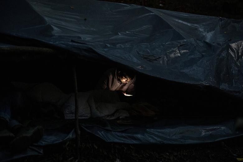 A migrant from Bangladesh checks his mobile phone in the woods near Velika Kladusa, Bosnia and Herzegovina. Hundreds of migrants from Asia, the Middle East and North Africa set up makeshift camps in Bosnian woods near the border with Croatia, attempting to cross into the European Union where they hope for a better life. REUTERS/Marko Djurica    